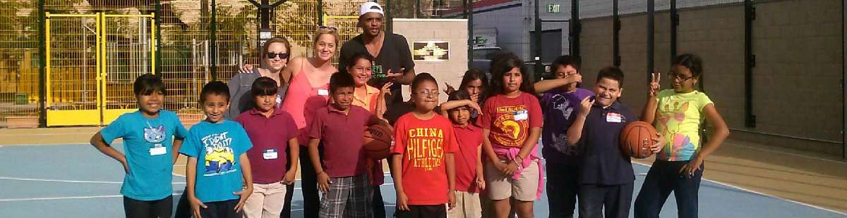Children and adults in a group photo on basketball court