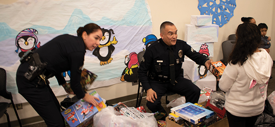 Two LAPD officers pass out gifts to young kids