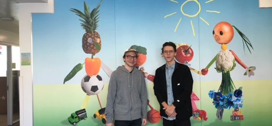 Two men from NBC Universal stand in front of a mural at Hope Street