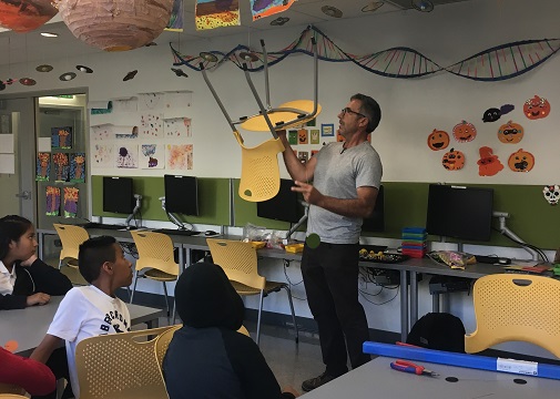 Artist Brad Howe balances a chair to teach the Hope Street Students about the use of gravity in art.