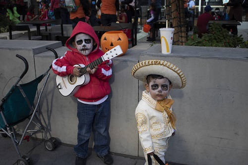 Two little boys dressed in Dia De Los Murertos Costumes strike a pose.